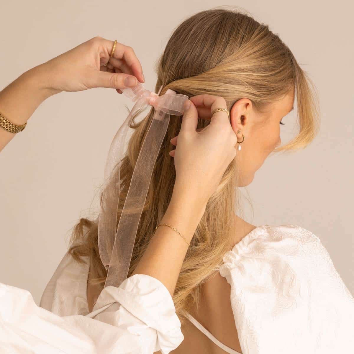 Rosa mini-hårklämma stylas i halvt uppsatt blont hår på modell i vit topp, fotograferad i studio