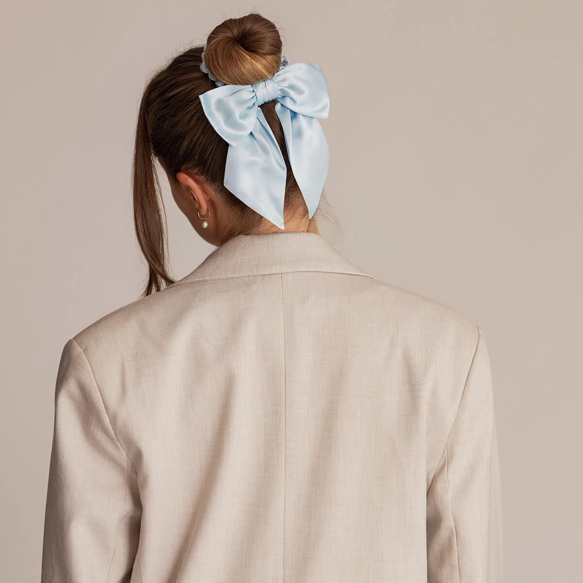 Ljusblå siden scrunchie med rosett i hög knut för styling som är både skonsam och stilren