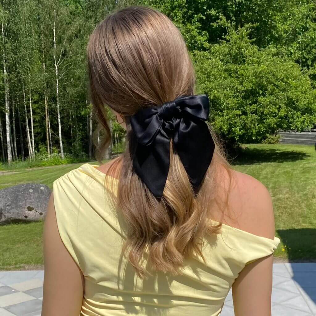 Sidenrosett-scrunchie i svart – uppsatt i halvt utsläppt hår utomhus